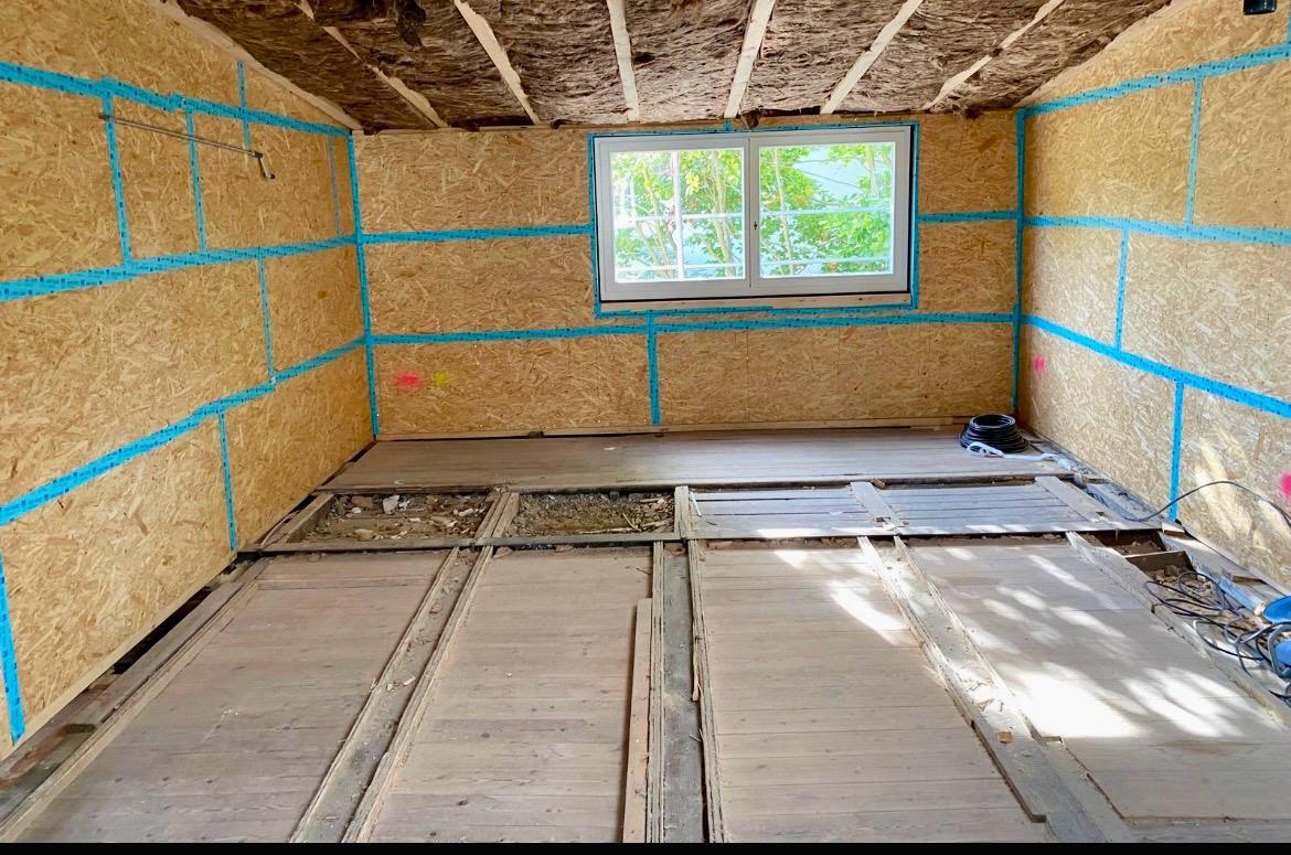Innenraum eines Gartenhauses mit gedämmten Wänden und erneuertem Holzboden