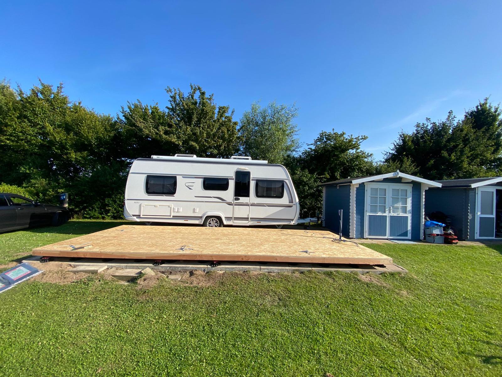 Wohnwagen auf einem neu gebauten Holzpodest auf einem Campingplatz