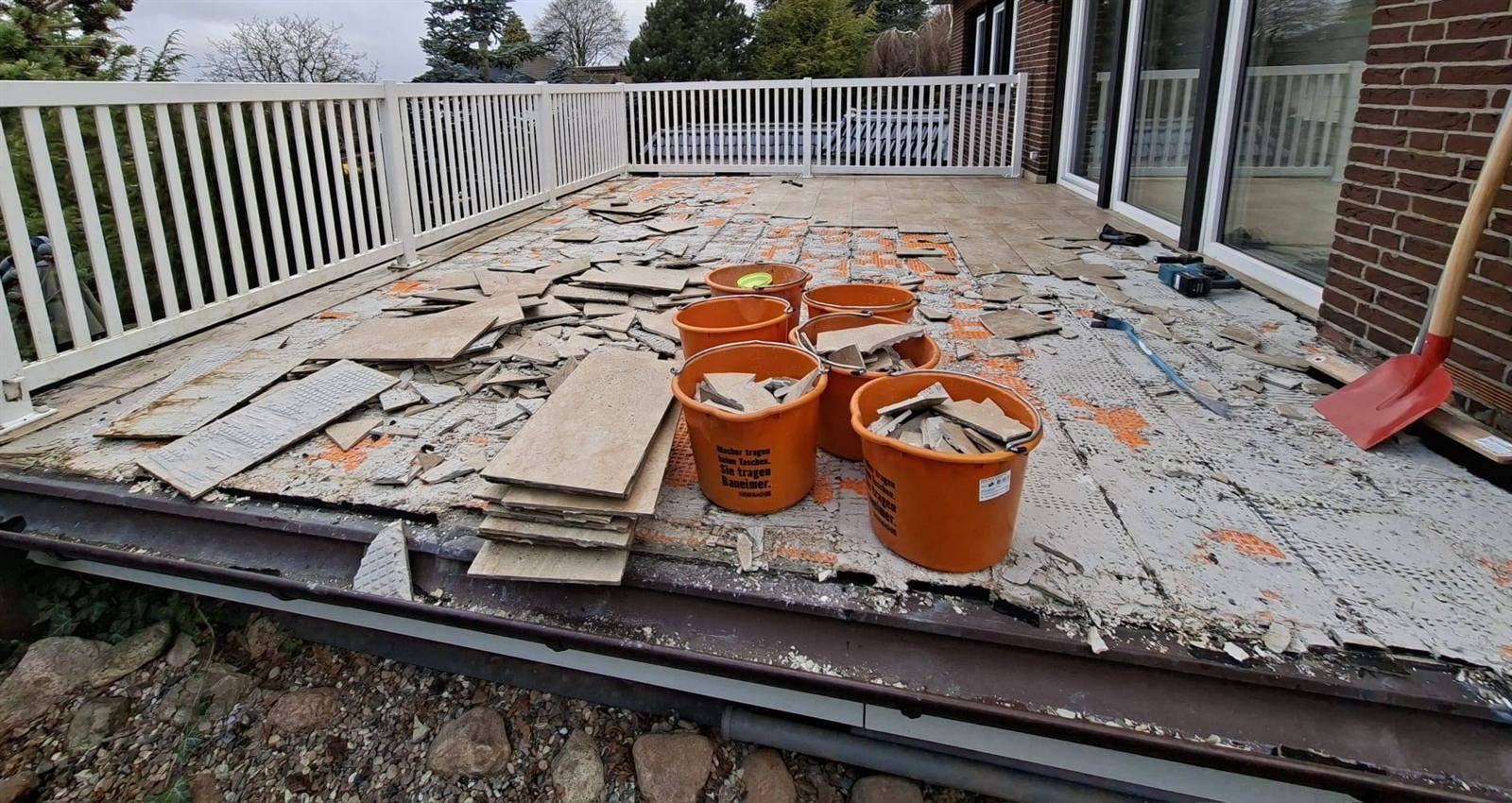 Terrasse vor der Sanierung: entfernter Fliesenbelag, Bauschutt in Eimern